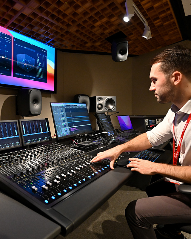 A man interacting with a musical dashboard, looking at multiple monitors.